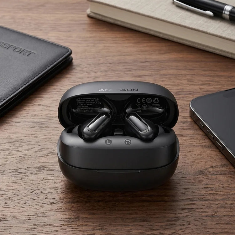 Black wireless earbuds in an open charging case on a wooden desk, surrounded by a notebook, pen, phone, and passport cover.