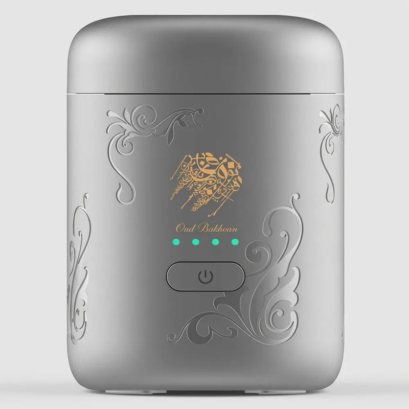 A silver cylindrical portable device with ornate embossed scrollwork and a gold bee logo, featuring a power button and four green LED indicator lights on the front.