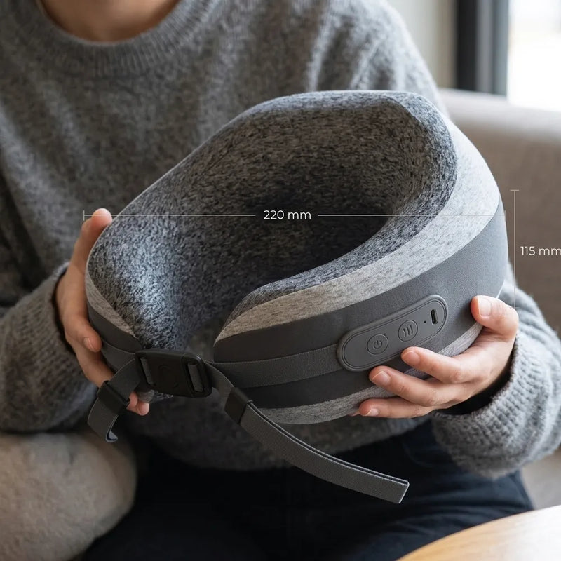 A person in a gray sweater holds a gray and black neck pillow with overlaid dimension lines showing 220 mm width and 115 mm height.