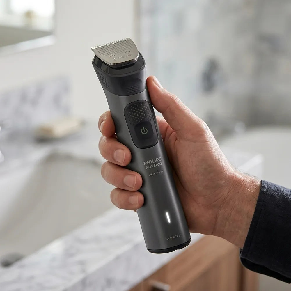 A hand holding a Philips hair trimmer in a bathroom setting with a blurred sink and countertop in the background.