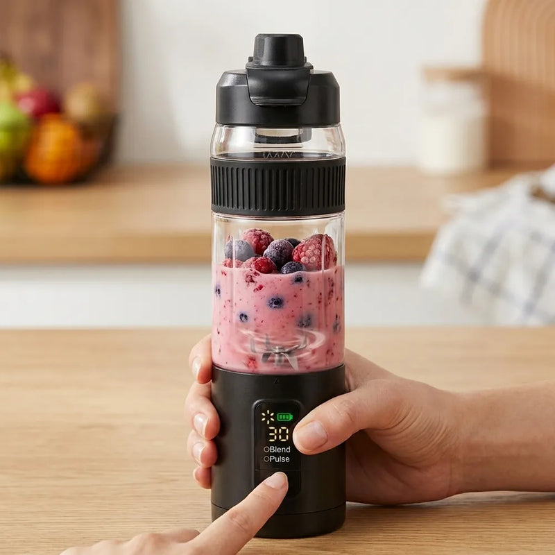 A person's hands holding a black and clear portable blender bottle filled with a pink berry smoothie and fresh berries, set on a wooden table with a blurred kitchen background.